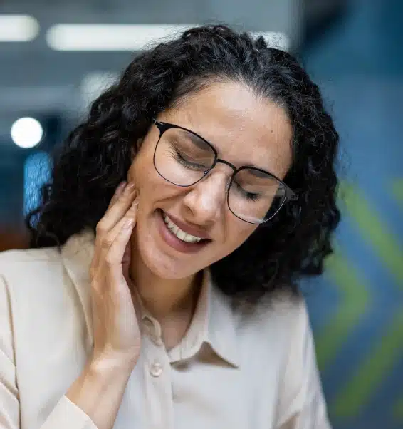 Woman with glasses smiling warmly in modern dental office setting.